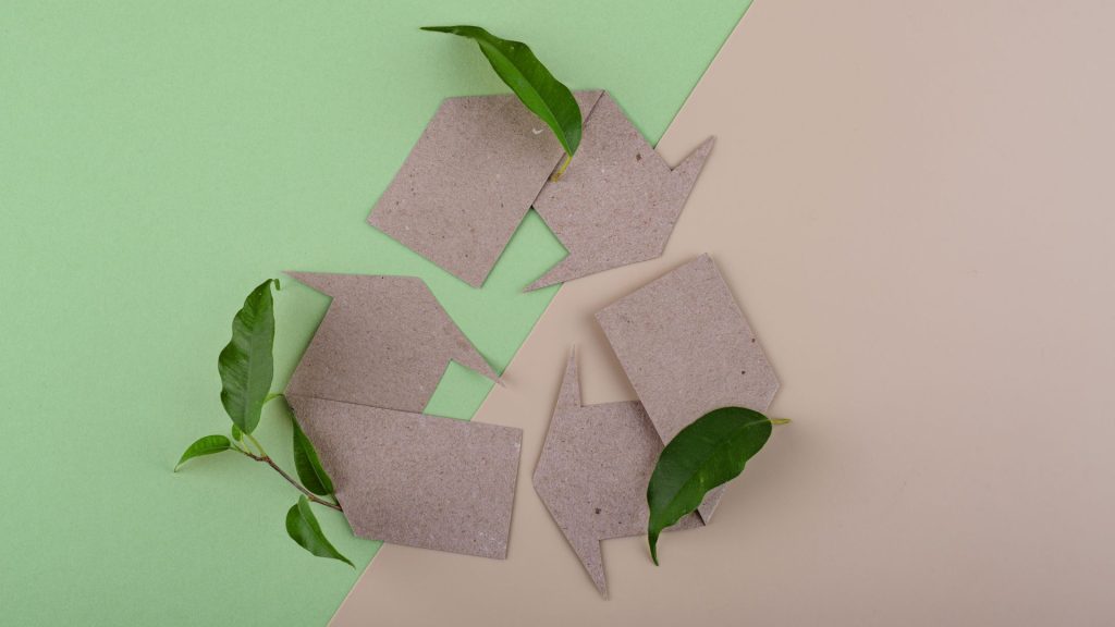 News, risorse e approfondimenti | Web Furniture Nell'immagine è presente il simbolo del riciclo rappresentato con il cartone e circondato da foglie che rimandano alla sostenibilità